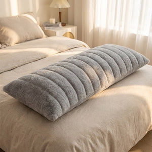 Traversin en peluche grise sur un lit chambre cocooning