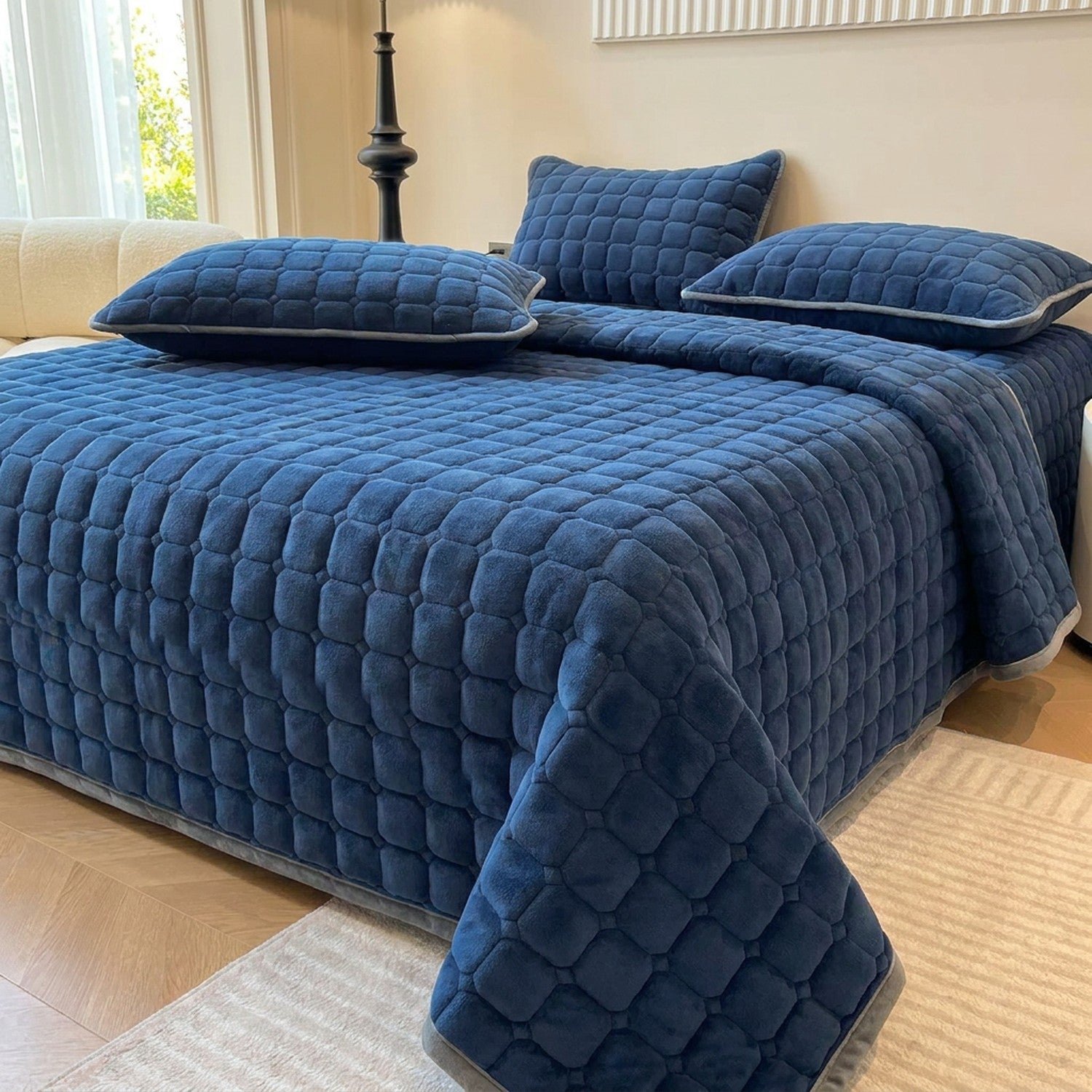 Couvre-lit matelassé velours bleu marine avec deux taies assorties sur un lit