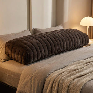 Traversin en peluche marron sur un lit chambre cocooning