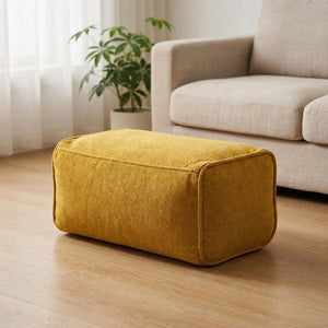 Pouf repose-pieds en chenille jaune moutarde dans un coin salon chaleureux