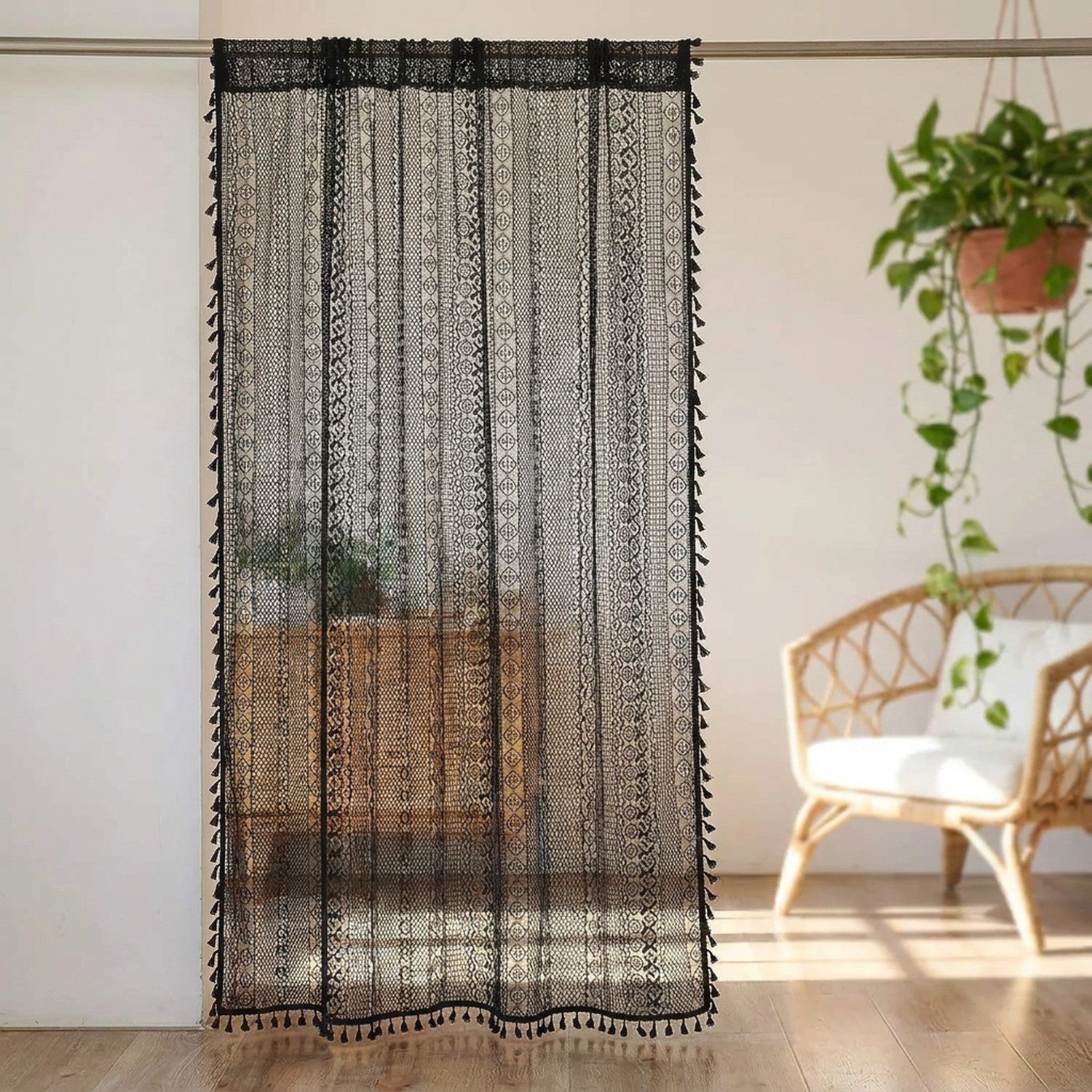 Rideau boho en dentelle au crochet noir à pompons suspendu à une fenêtre