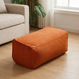 Pouf repose-pieds en chenille orange dans un salon minimaliste lumineux