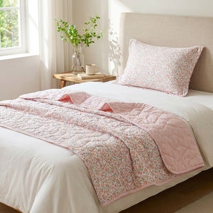 Couette d'été matelassée rose à motif floral installée sur un lit