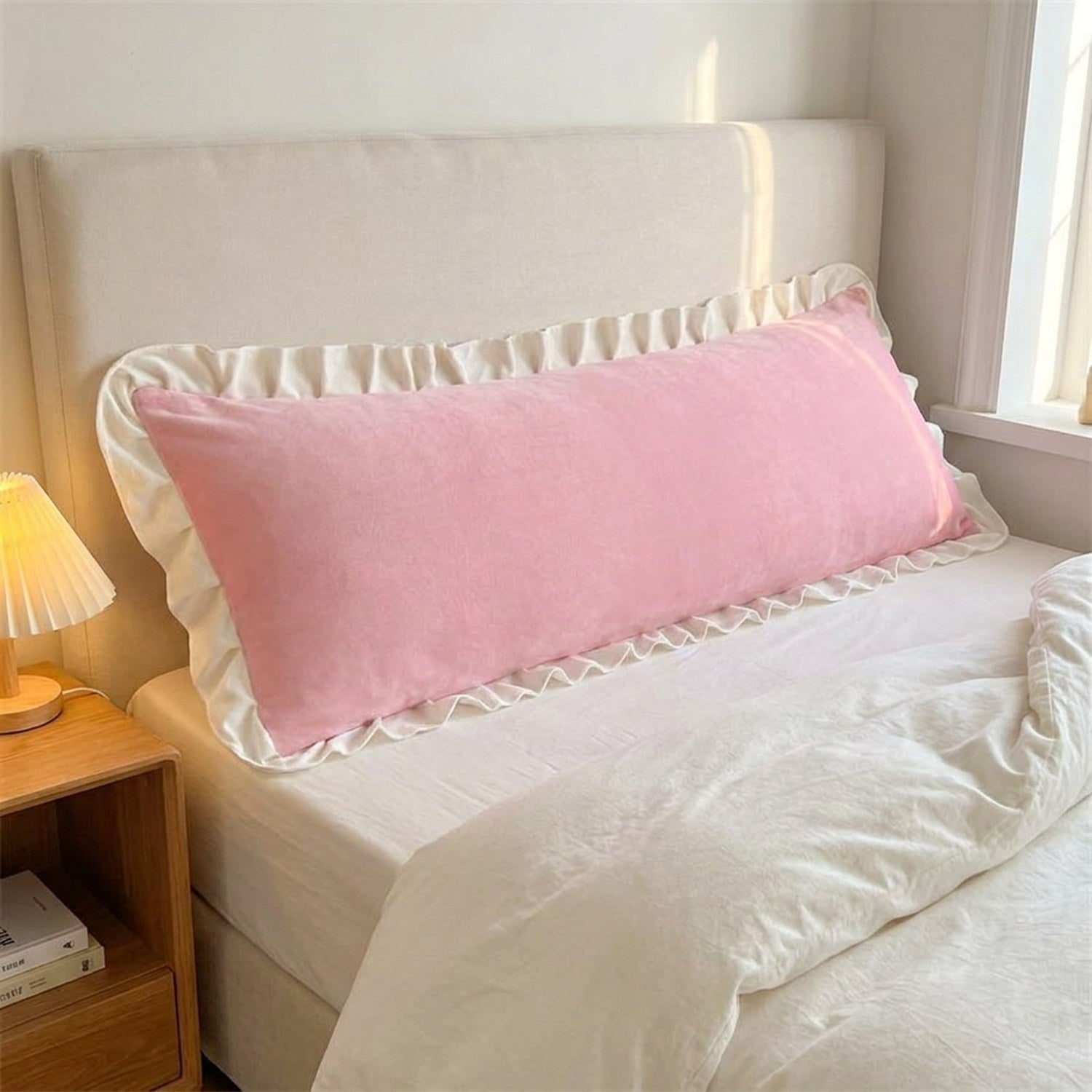 Taie de traversin en velours rose poudré à volant blanc sur un lit double
