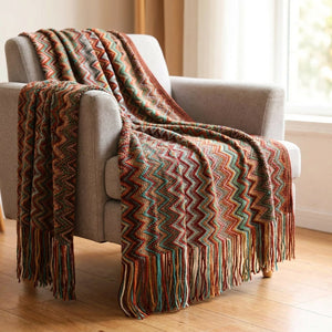 Plaid tricoté chevrons coloris rouge drapé sur un fauteuil gris