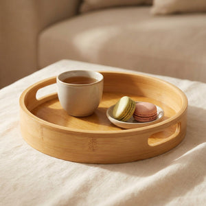 Plateau de service rond en bambou avec thé et macarons sur du linge clair