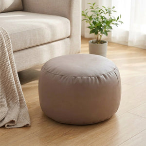 Pouf marocain rond en simili cuir taupe dans un salon lumineux