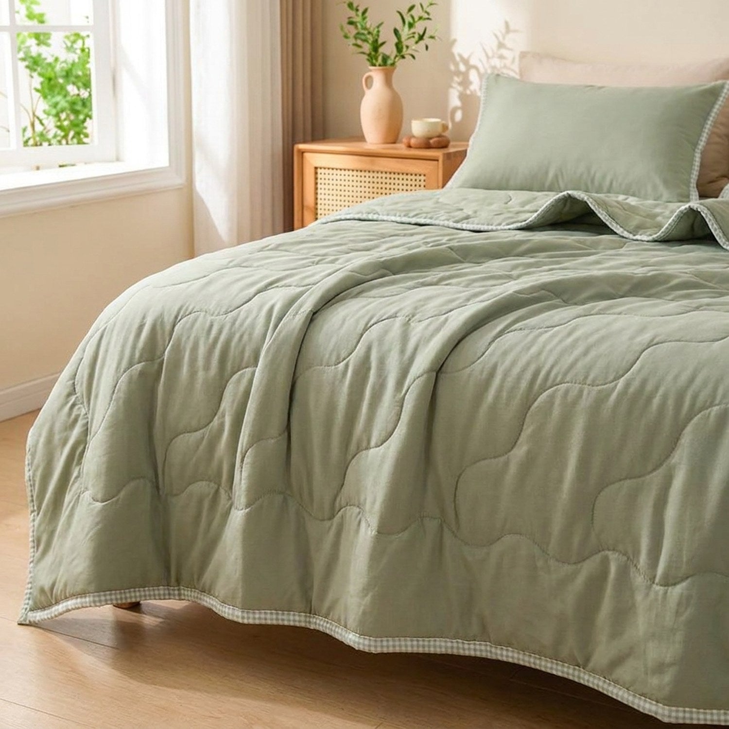 Couette d'été matelassée vert sauge uni installée sur un lit