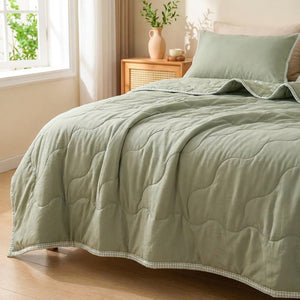 Couette d'été matelassée vert sauge uni installée sur un lit