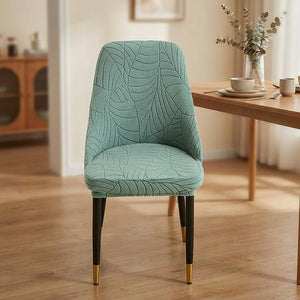 Housse de chaise extensible en jacquard vert sauge au motif feuilles sur une chaise incurvée