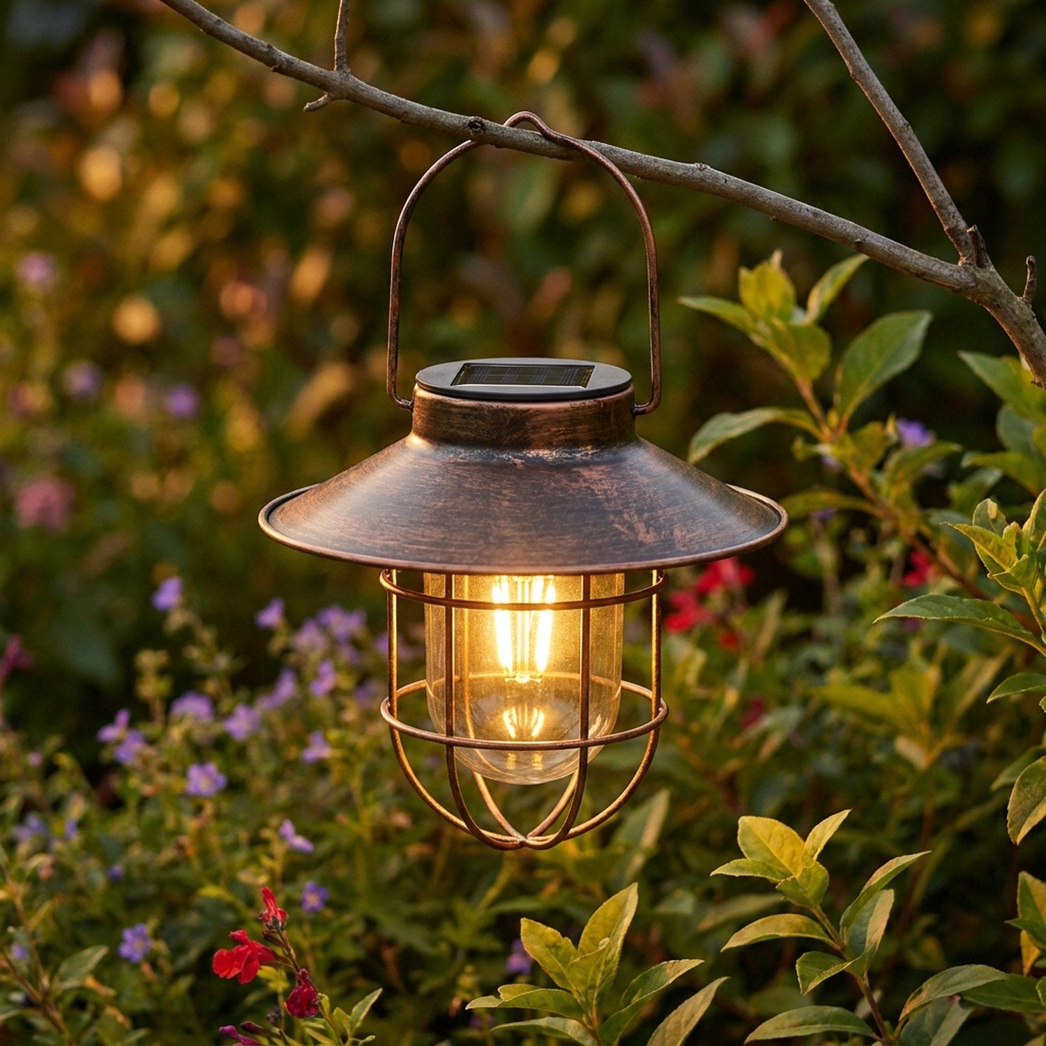 Lanterne solaire bronze allumée suspendue à une branche dans un jardin