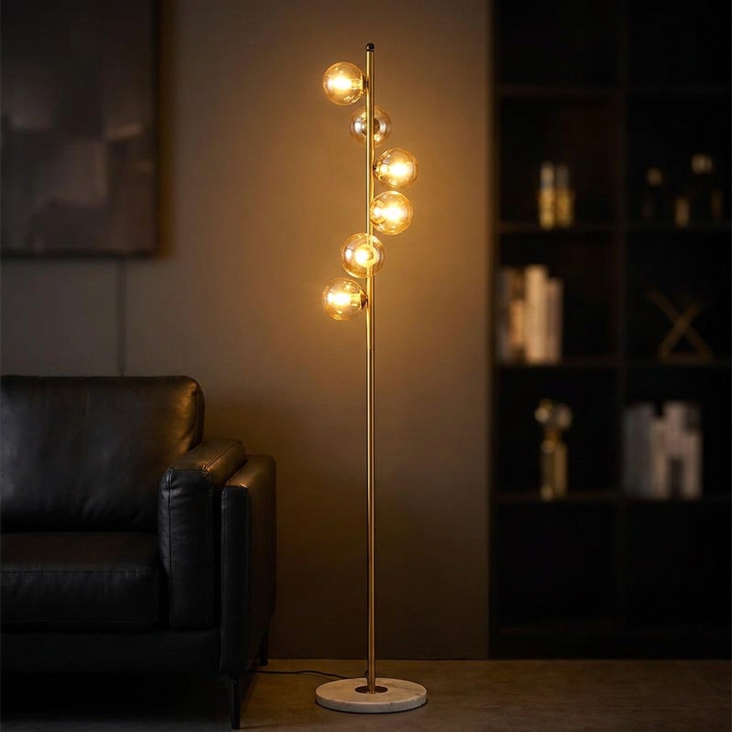 Lampadaire à 5 boules de verre ambrées transparentes sur tige dorée allumé dans une ambiance chaleureuse