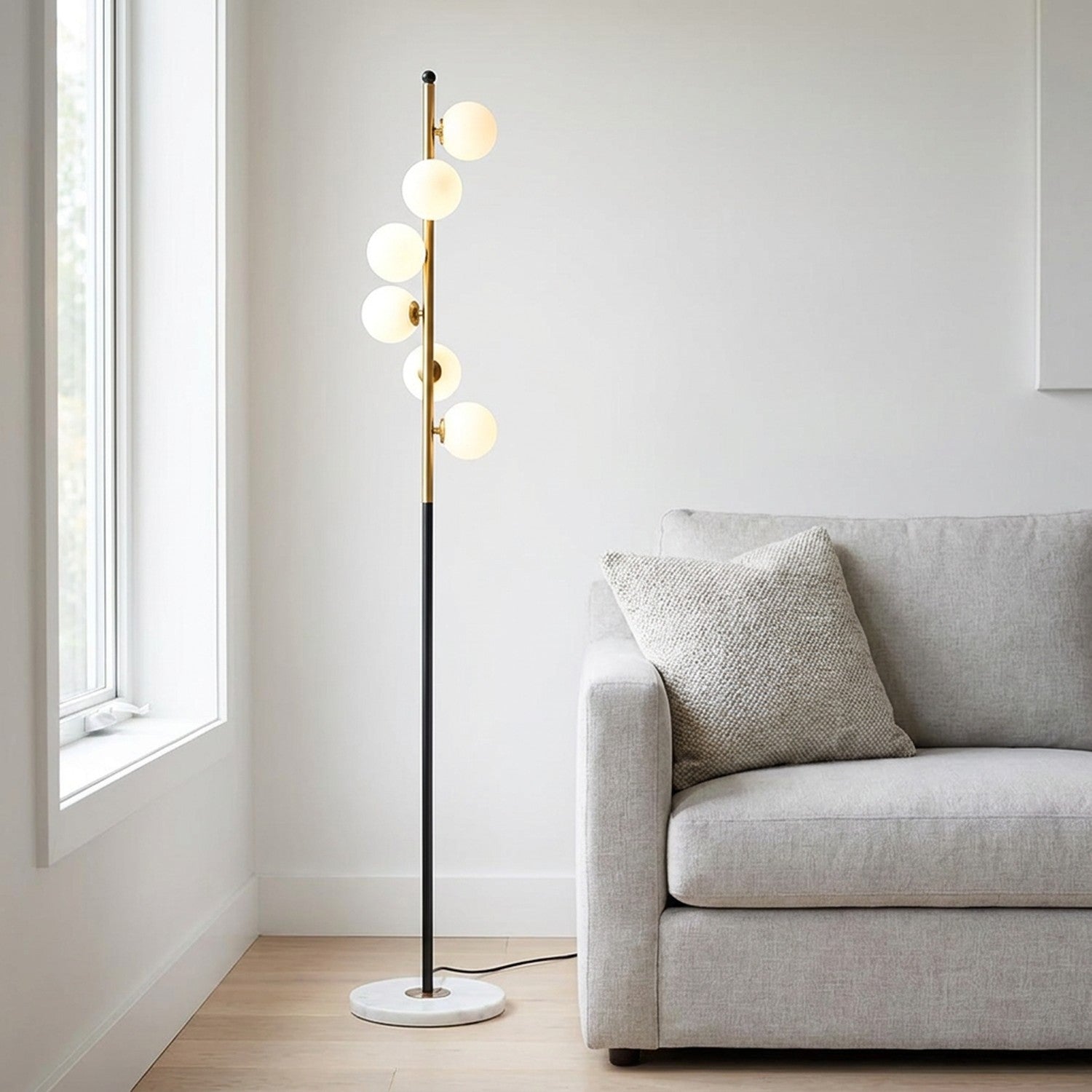 Lampadaire à 5 boules de verre blanc laiteux sur tige noire et dorée dans un salon moderne
