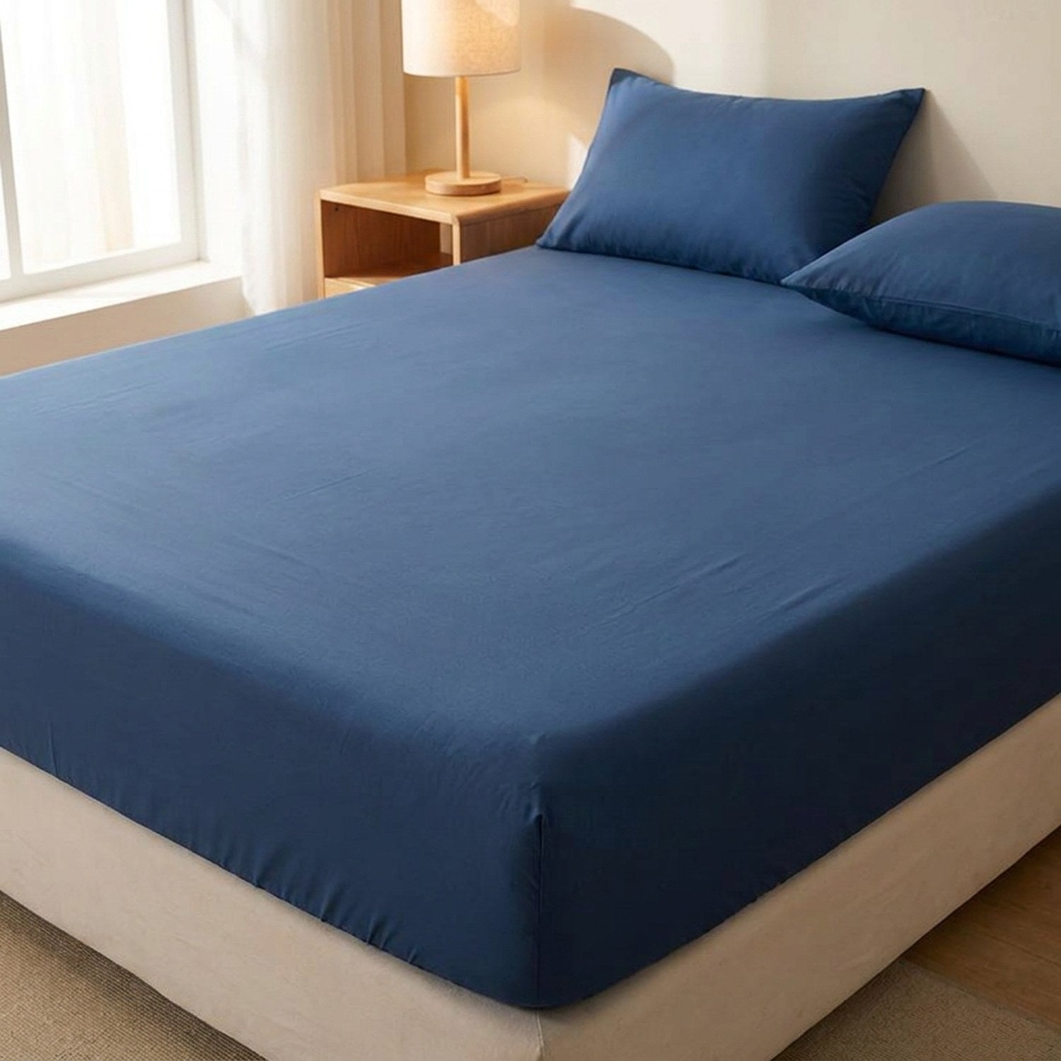 Drap housse bleu foncé délavé installé sur un matelas dans une chambre chaleureuse
