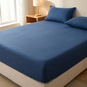 Drap housse bleu foncé délavé installé sur un matelas dans une chambre chaleureuse
