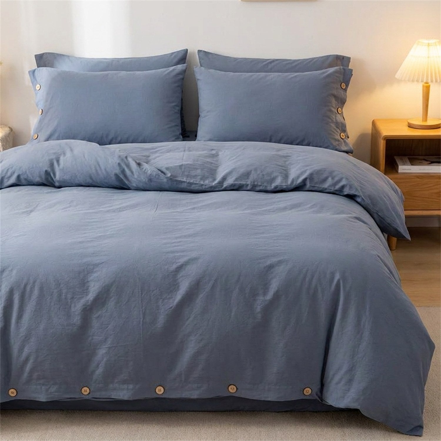 Housse de couette bleue en coton avec boutons en bois posée sur un lit