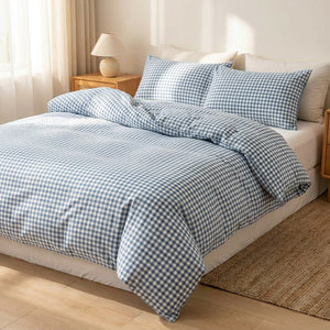 Housse de couette à carreaux vichy bleus posée sur un lit fait dans une chambre lumineuse et chaleureuse