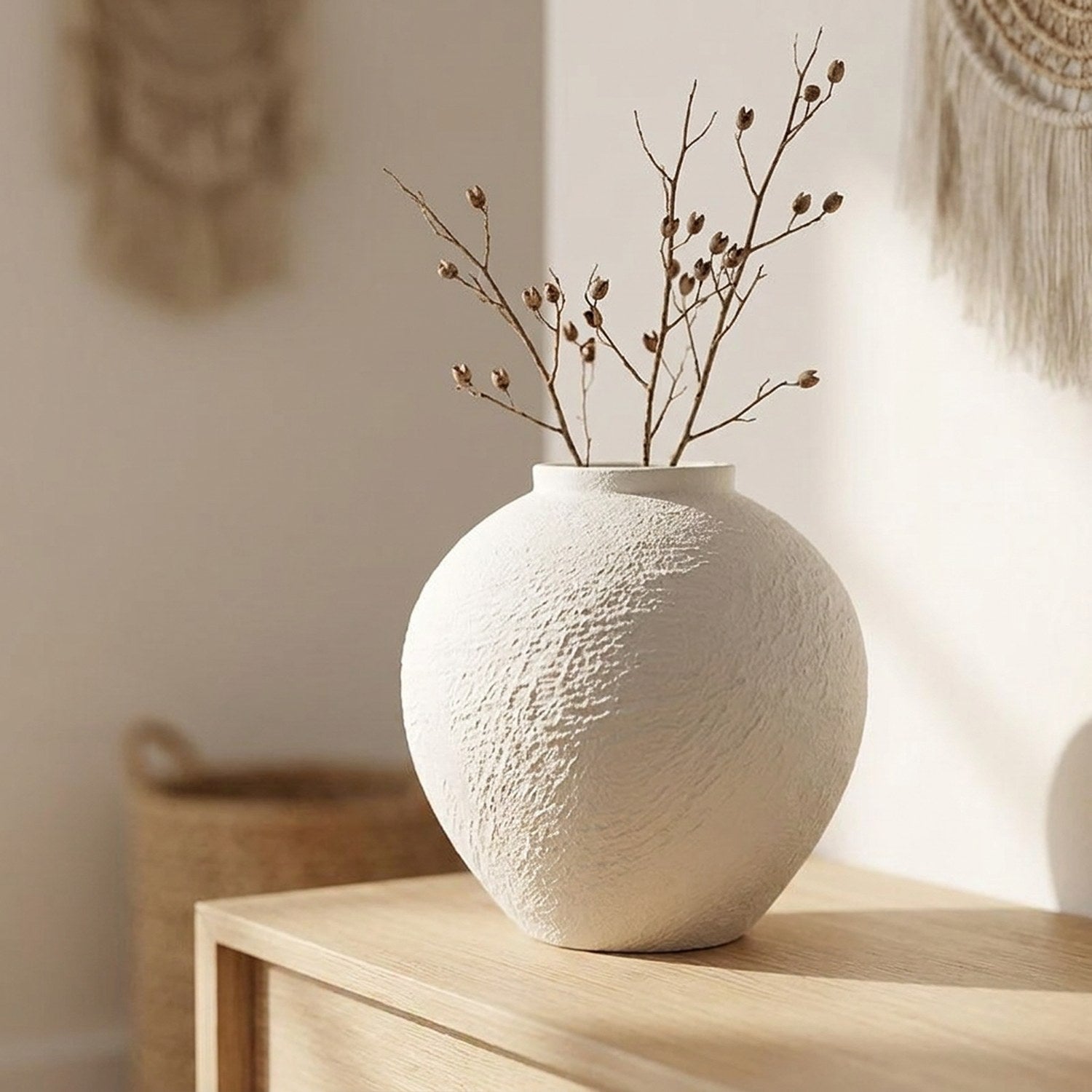 Vase en céramique blanche texture brute avec des branches séchées sur une console