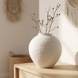 Vase en céramique blanche texture brute avec des branches séchées sur une console