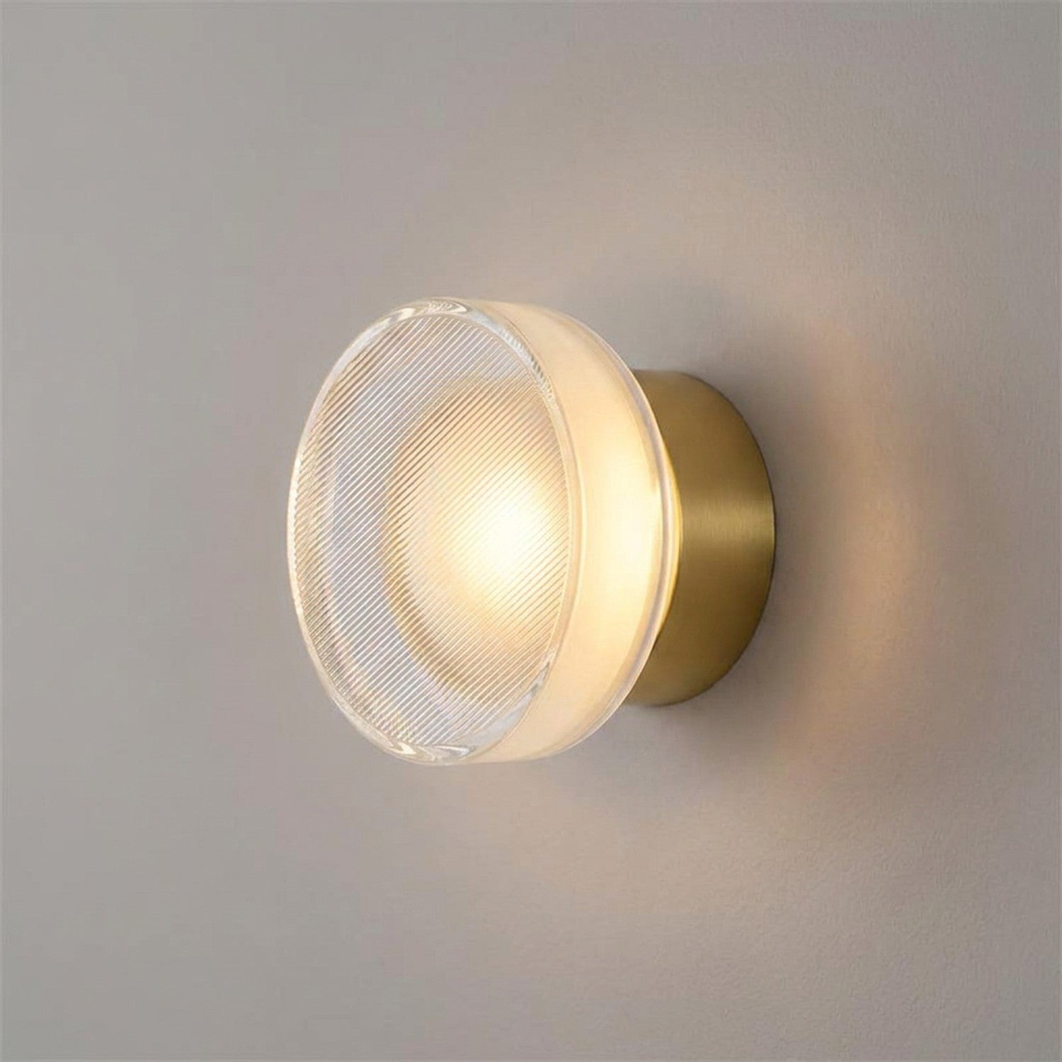 Applique murale LED dorée au verre strié gros plan sur mur clair