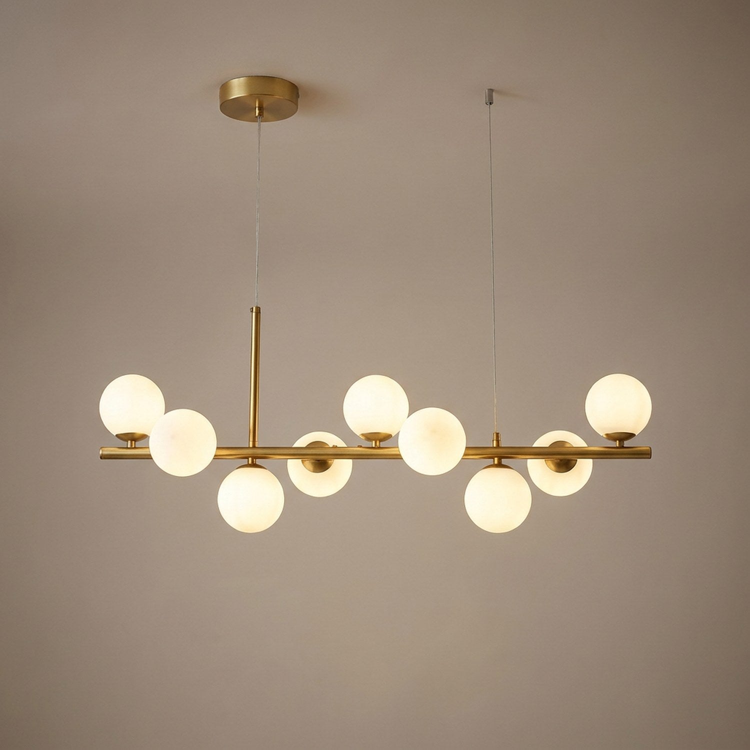 Lustre boule de verre finition dorée allumé sur fond neutre chaleureux