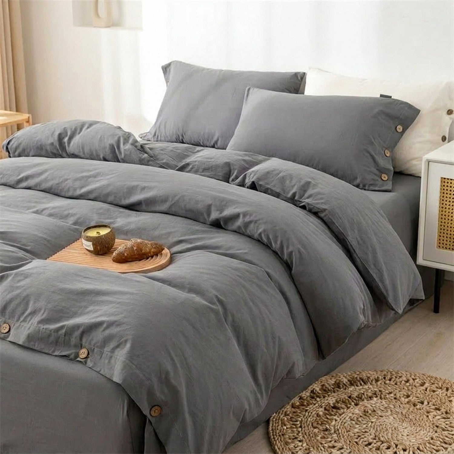 Housse de couette grise en coton avec boutons en bois posée sur un lit