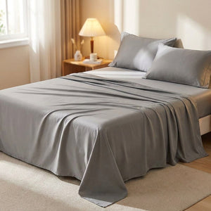 Drap plat en coton égyptien gris posé sur un lit fait dans une chambre lumineuse et chaleureuse