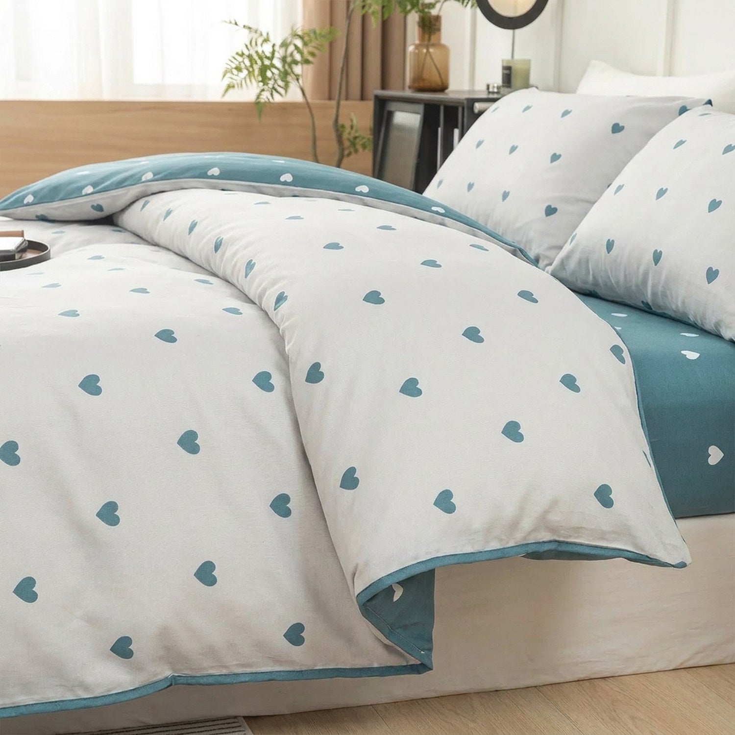 Housse de couette grise à petits cœurs turquoise avec taies assorties sur un lit