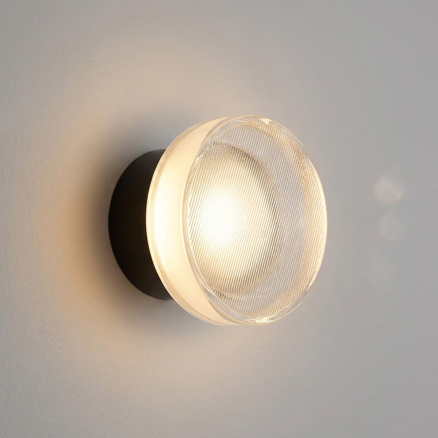 Applique murale LED noire au verre strié gros plan sur mur clair