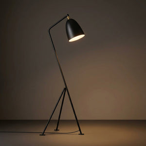 Lampadaire trépied noir sur fond neutre mettant en valeur son design scandinave