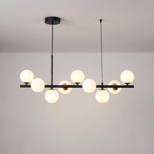 Lustre boule de verre finition noire et dorée allumé sur fond neutre chaleureux