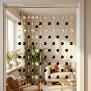 Rideau de perles aux boules de verre noires et transparentes suspendu dans une porte