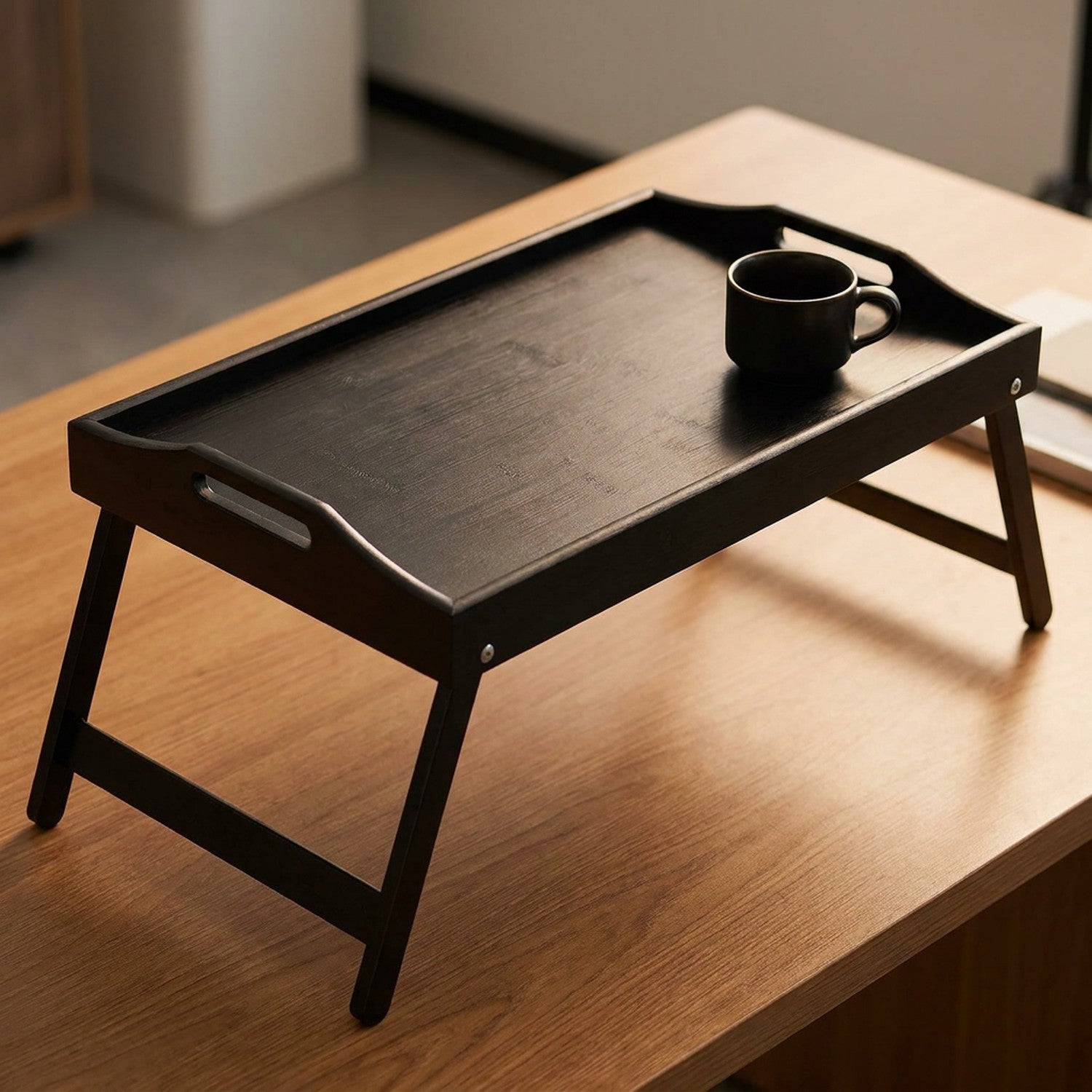 Plateau bambou noir avec pieds pliables sur un bureau en bois avec une tasse à café