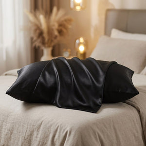 Taie d'oreiller en soie noire drapée sur un lit dans une chambre chaleureuse