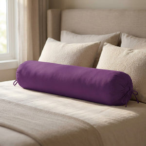 Traversin cylindrique violet posé sur un lit contre une tête de lit