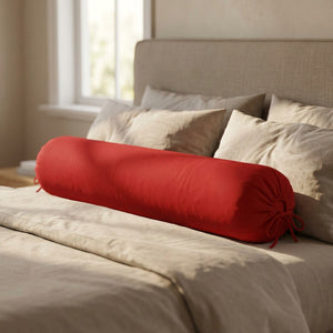 Traversin cylindrique rouge posé sur un lit contre une tête de lit
