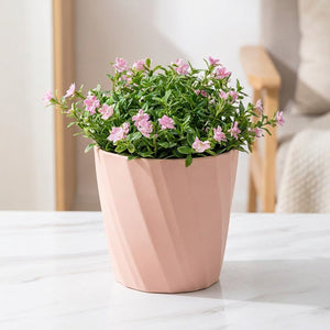 Cache-pot décoratif rose nervuré avec plante fleurie dans salon nordique