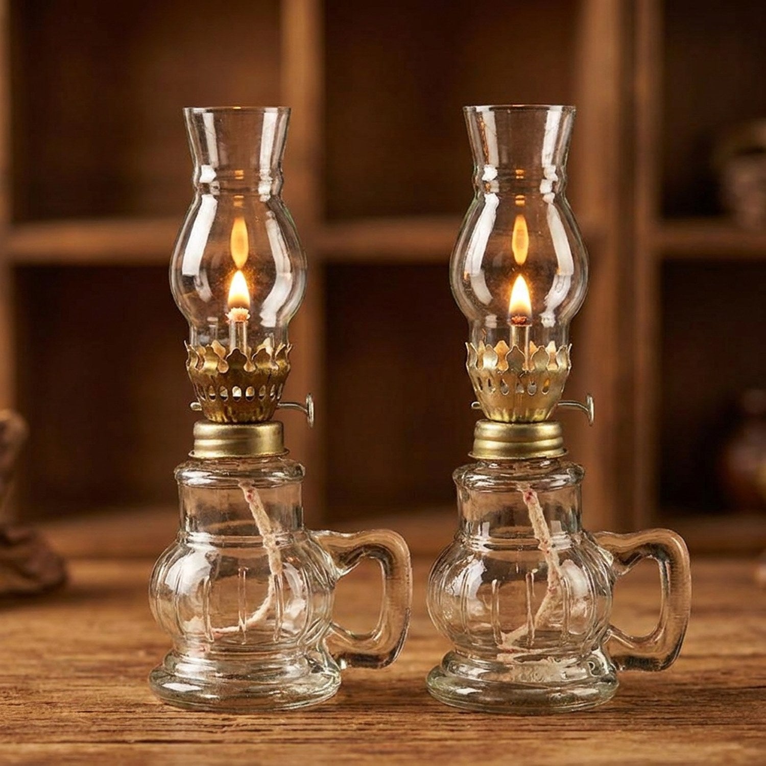 Deux lampes à pétrole en verre transparent allumées côte à côte
