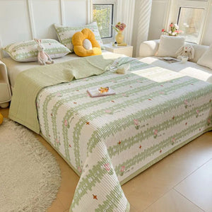 Couvre-lit matelassé coloris vert clair motifs floraux sur un lit