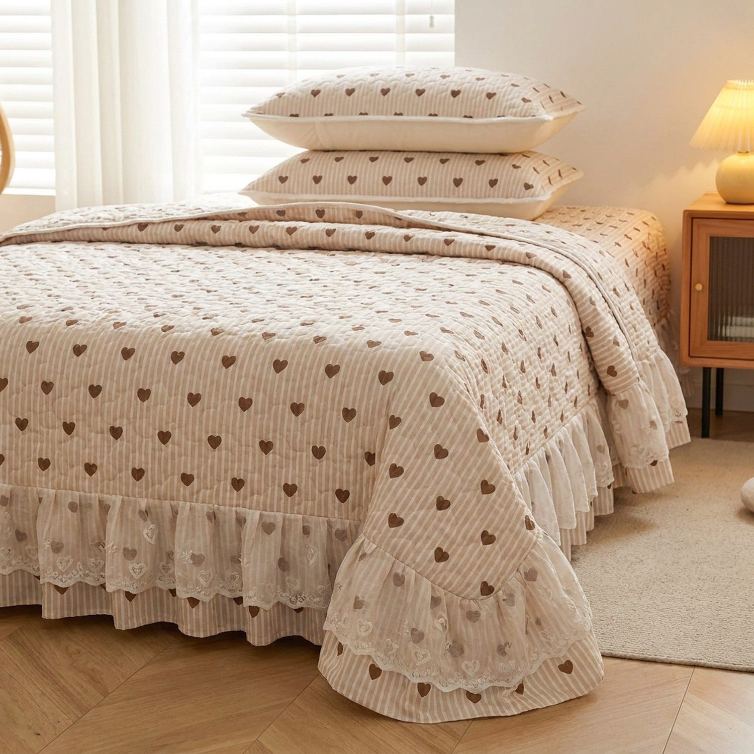 Couvre-lit beige rayé à petits coeurs sur lit fait