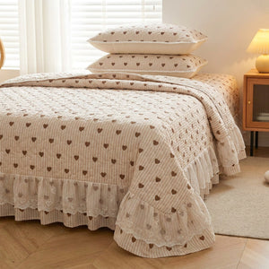 Couvre-lit beige rayé à petits coeurs sur lit fait