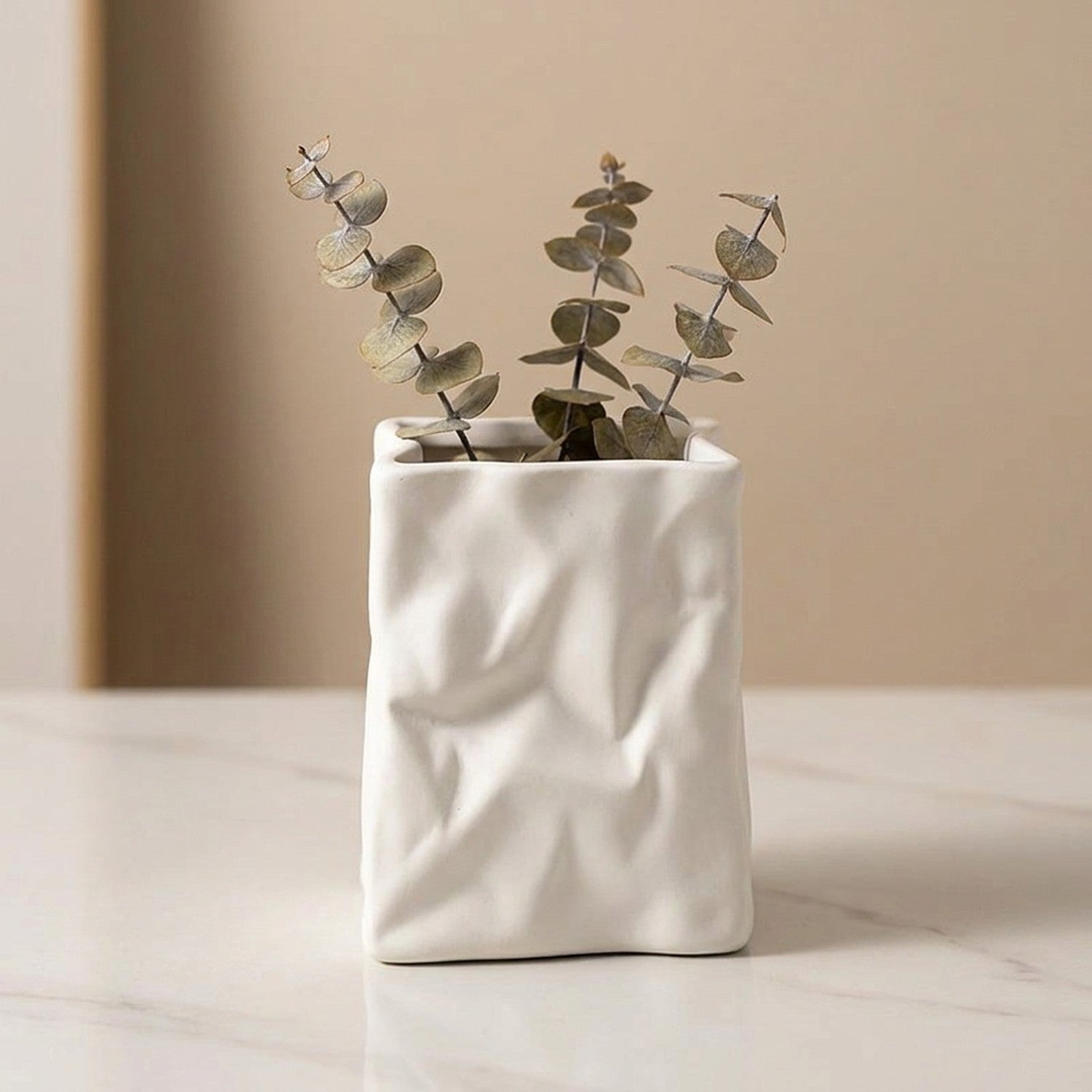 Vase froissé blanc seul avec eucalyptus sur marbre, vue rapprochée