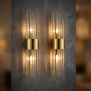 Paire d'appliques murales cristal et doré allumées sur un mur foncé