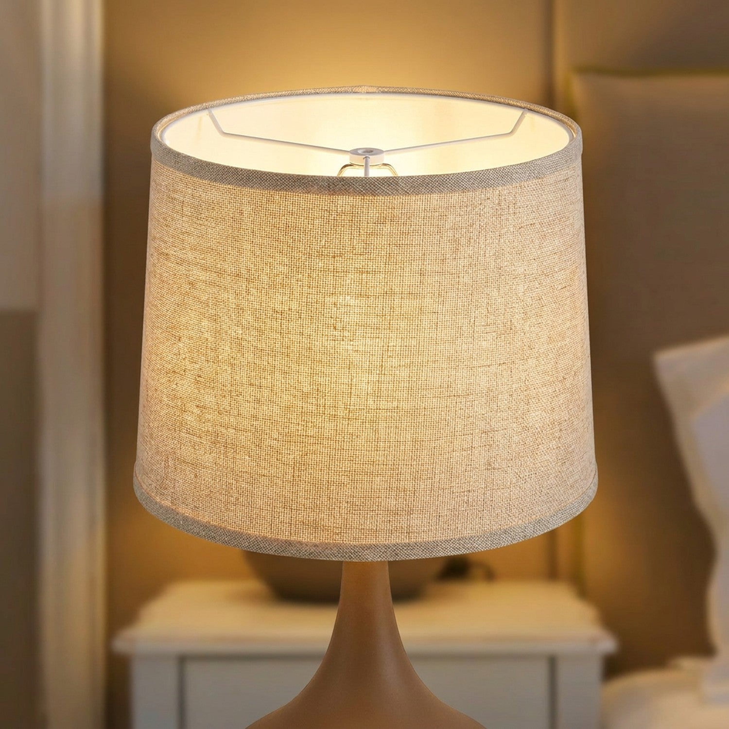 Abat-jour tambour tissu lin beige en gros plan avec texture visible et lumière chaude