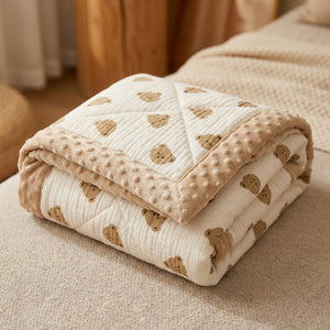 Couette bébé beige motif ours repliée montrant la bordure douce