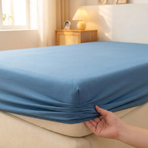 Drap housse bleu installé sur un lit avec bande élastique visible