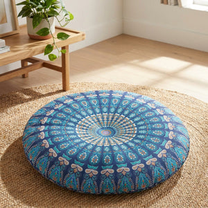 Housse de coussin ronde motif mandala bleu paon posée sur un tapis bohème