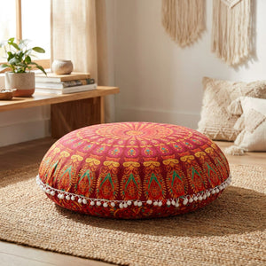 Housse de coussin ronde motif mandala corail posée sur un tapis bohème