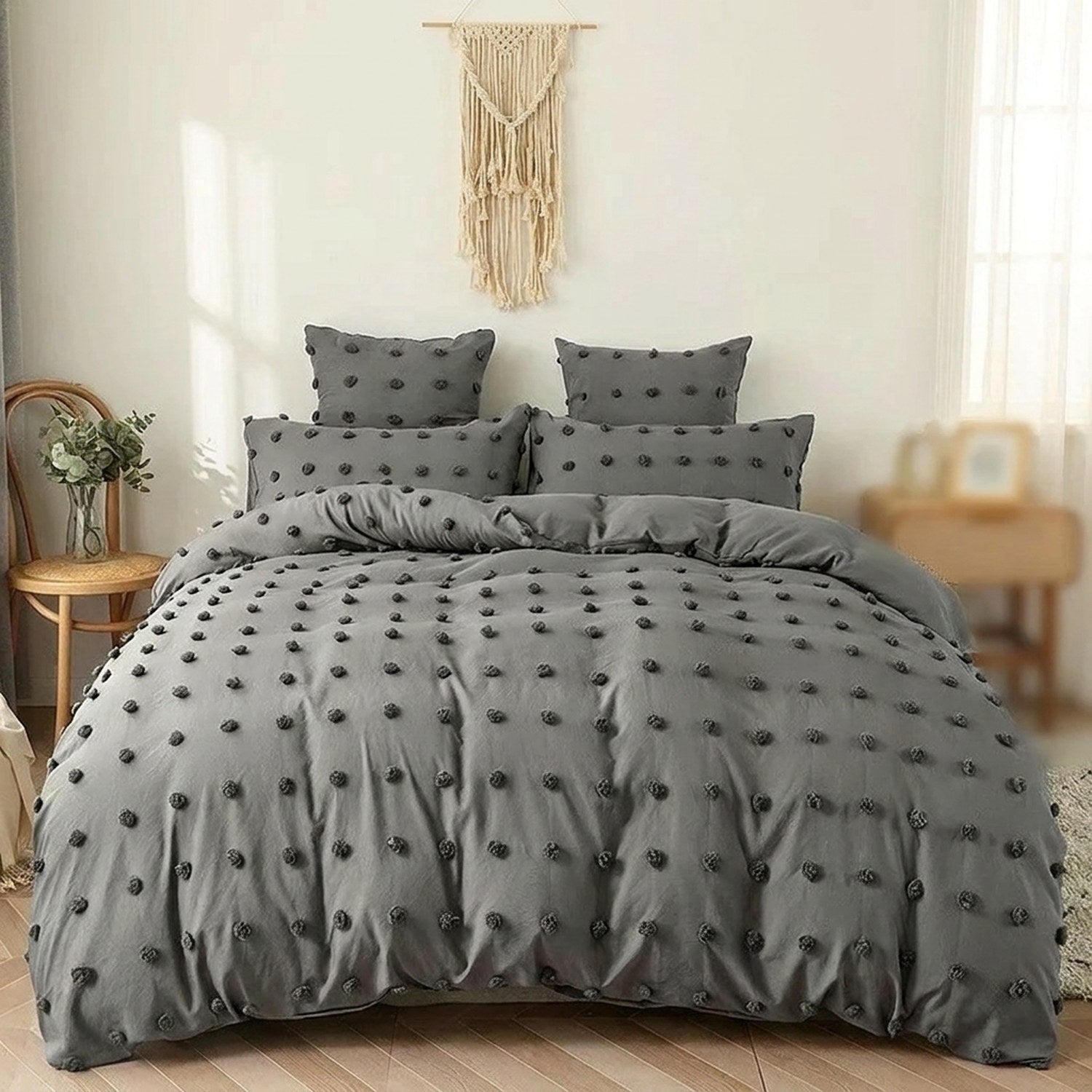 Parure de lit grise à pompons installée sur un lit dans une chambre bohème