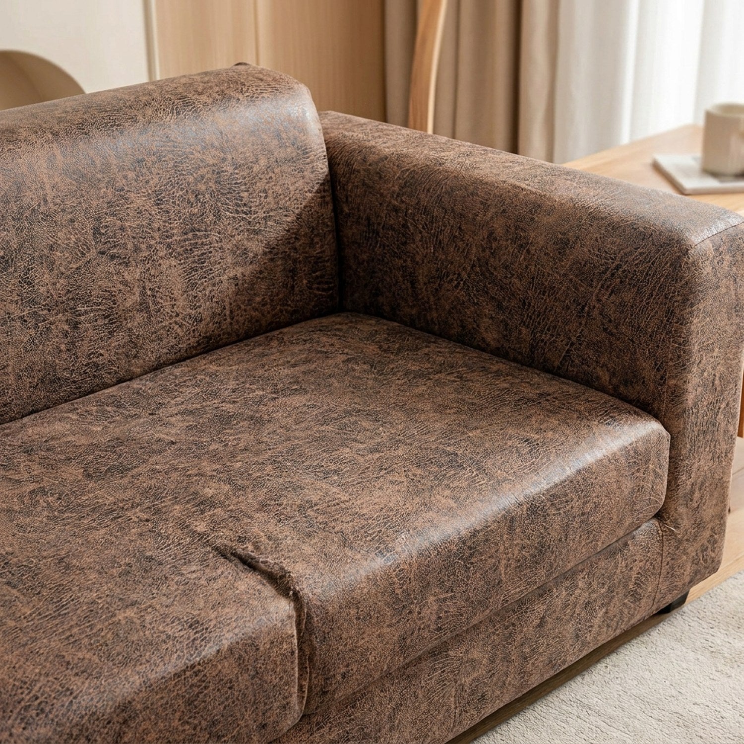 Housse de canapé marron effet cuir vieilli, gros plan sur l'assise et l'accoudoir